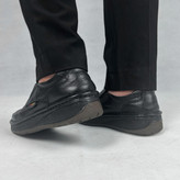 نمایی نزدیک از کفش طبی مردانه مدل کلارک، تماماً مشکی، ساخته شده از چرم طبیعی با جزئیات دوخت ظریف. طراحی ارگونومیک و کفی تخصصی برای حداکثر راحتی و حمایت قوس پا در استفاده روزانه طولانیمدت