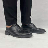 تصویر کفش کالج مردانه (Loafer) مشکی مدل هشترک پوشیده شده روی پای یک مرد، با جزئیات نمایان از جنس چرم و طراحی مدرن